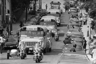 Police escort school buses as they leave South Boston High School on the second day of court-ordered busing on Sept. 14, 1974. Some buses were stoned and several arrests were made. (AP Photo)