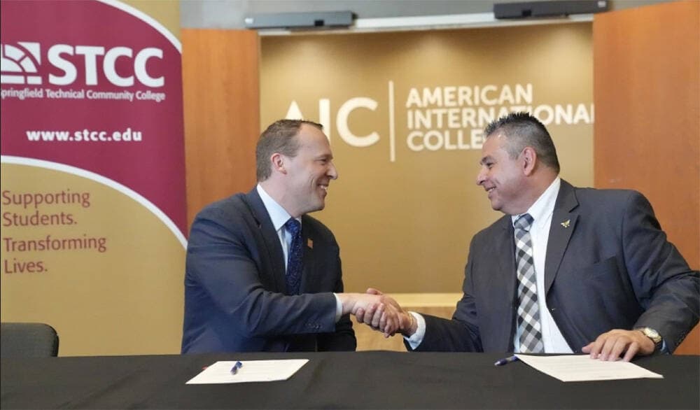 Springfield Technical Community College President John Cook shakes hands with American International College President Hubert Benitez after signing an on-campus housing agreement for STCC students on the AIC campus. (Courtesy American International College)