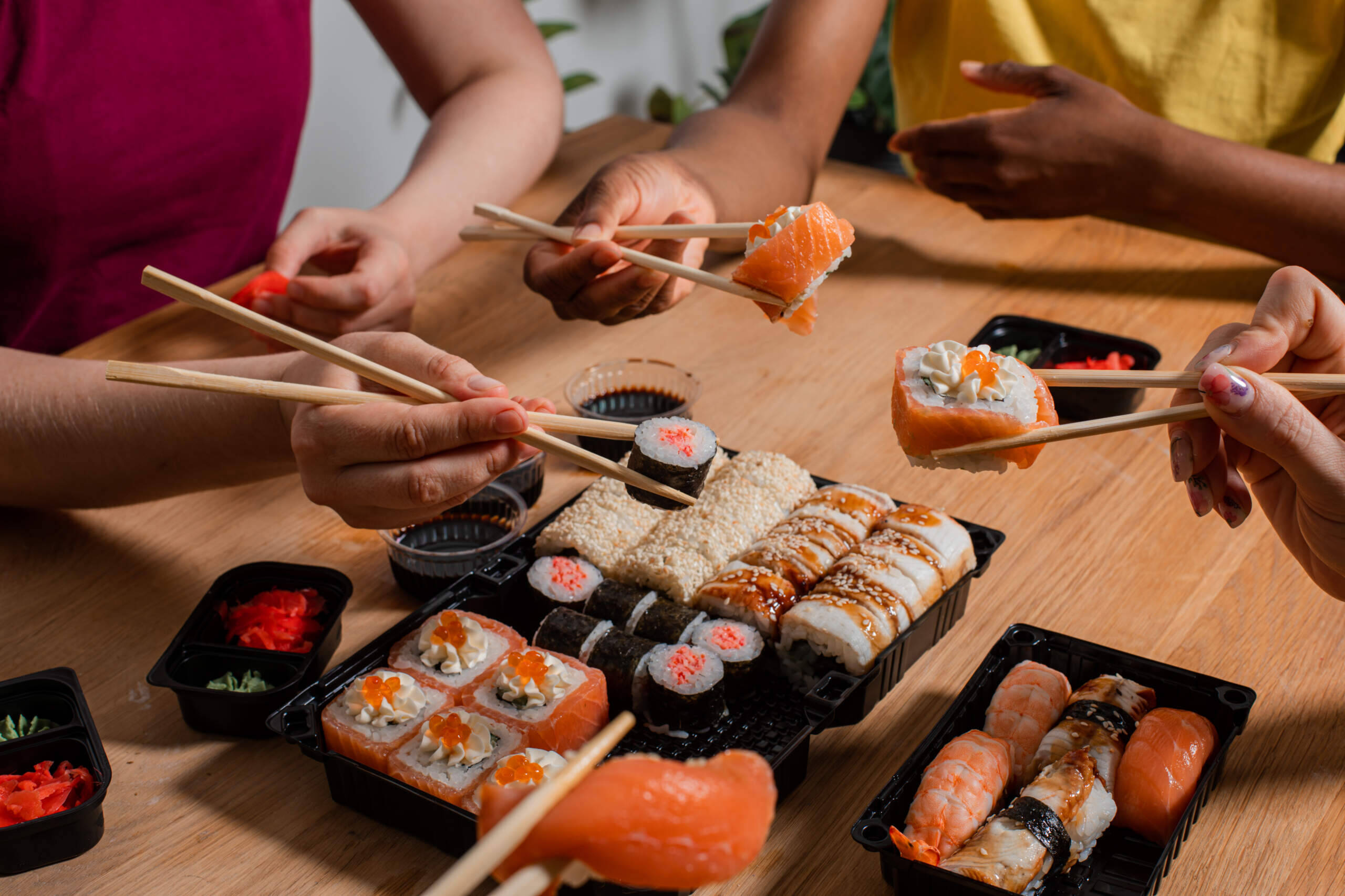 A group of people eat sushi together. (Oksana Shufrych via GettyImages)