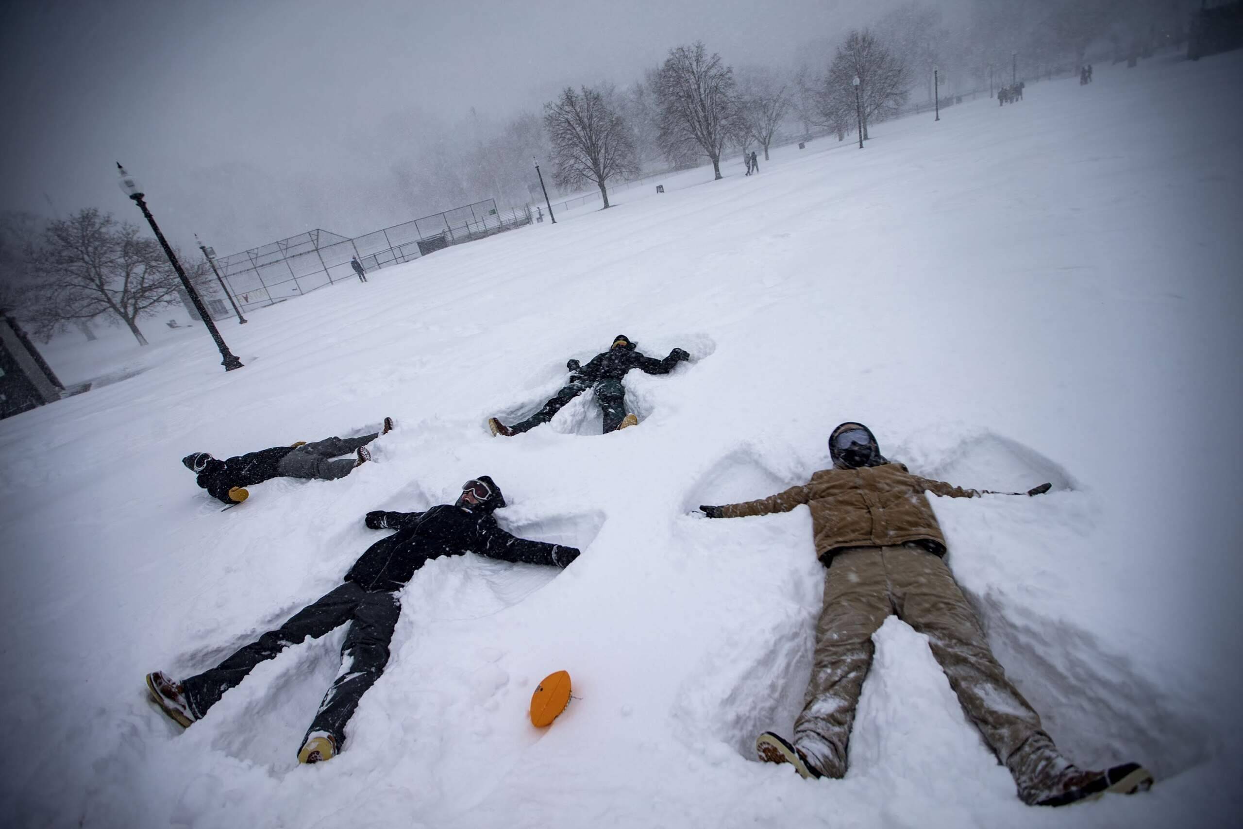 Four Wentworth students make snow angels in the snow in the Boston Common during the snowstorm. (Jesse Costa/WBUR)