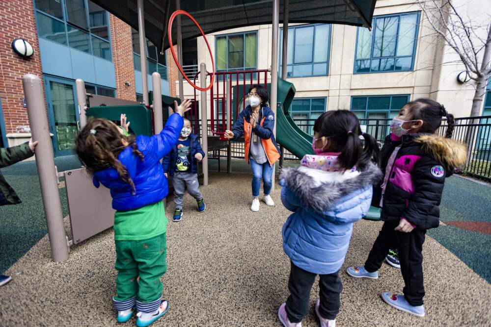 Young children play with their teacher outside of a child care center in 2022. (Jesse Costa/WBUR)