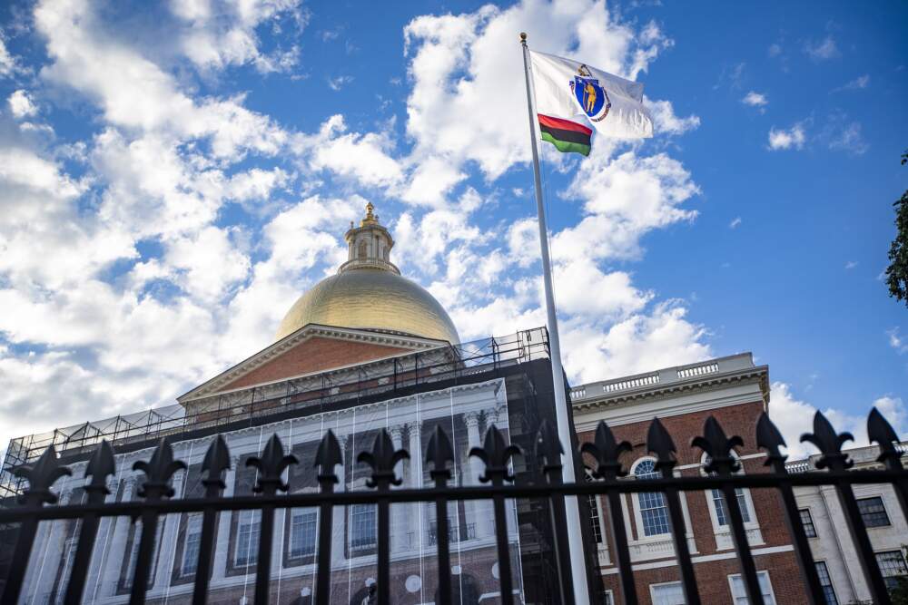 A red, black and green Pan-African flag flies beneath the Massachusetts state flag in front of the State House to commemorate the first Juneteenth holiday recognized by the state in 2021. (Jesse Costa/WBUR)