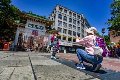 Anist Stevens, 10, poses for a photo for her mother, Shan Shan, in front of the Chinatown Gate during a visit to Boston from Las Vegas. (Jesse Costa/WBUR)