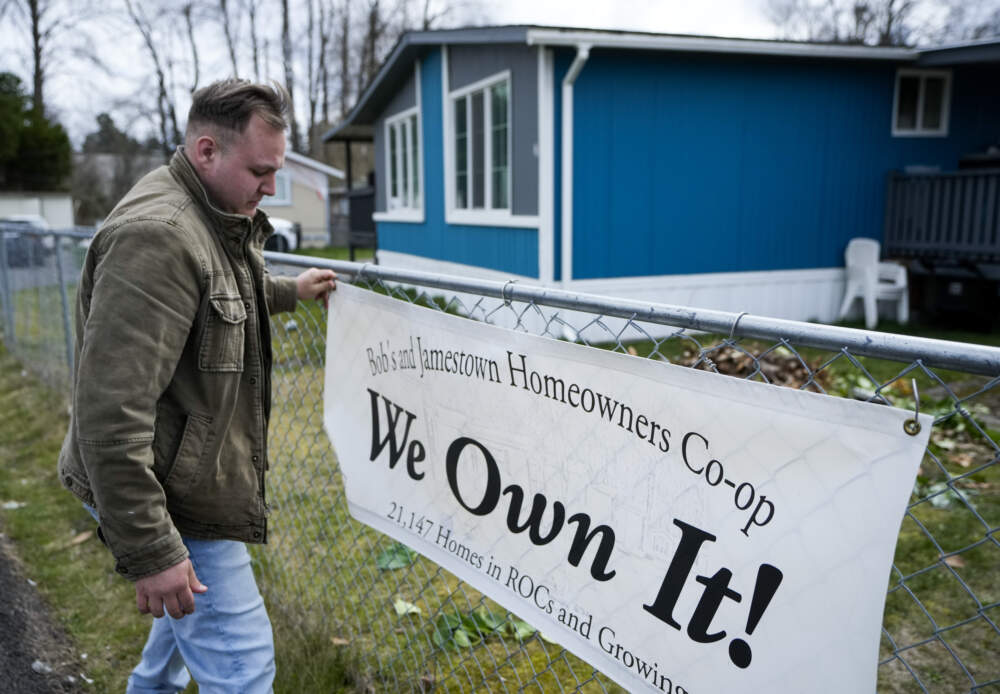 Gadiel Galvez, 22, adjusts a sign stating that his resident cooperative owns their mobile home park. (Lindsey Wasson/AP)