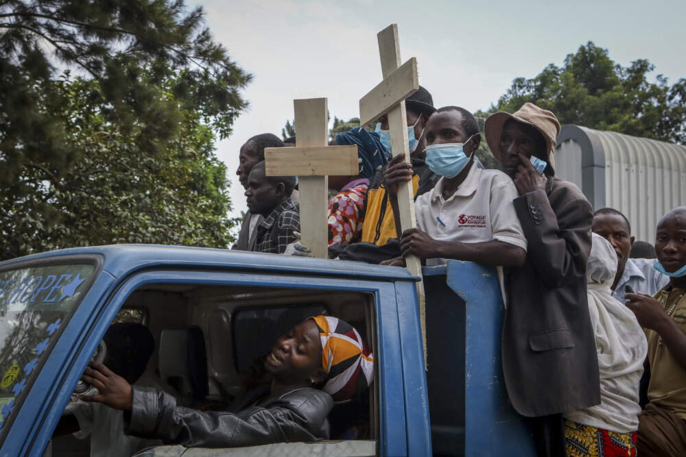 Relatives ride in the back of a truck with the coffins of villagers who were killed by suspected rebels as they retreated from Saturday's attack on the Lhubiriha Secondary School. (Hajarah Nalwadda/AP)
