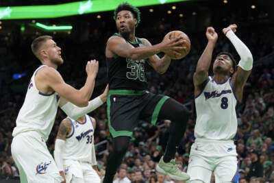 Celtics guard Marcus Smart looks to pass past Washington Wizards center Kristaps Porzingis. A person with knowledge of the deal says the Wizards have agreed to trade Porzingis to the Celtics.  (Steven Senne, AP)
