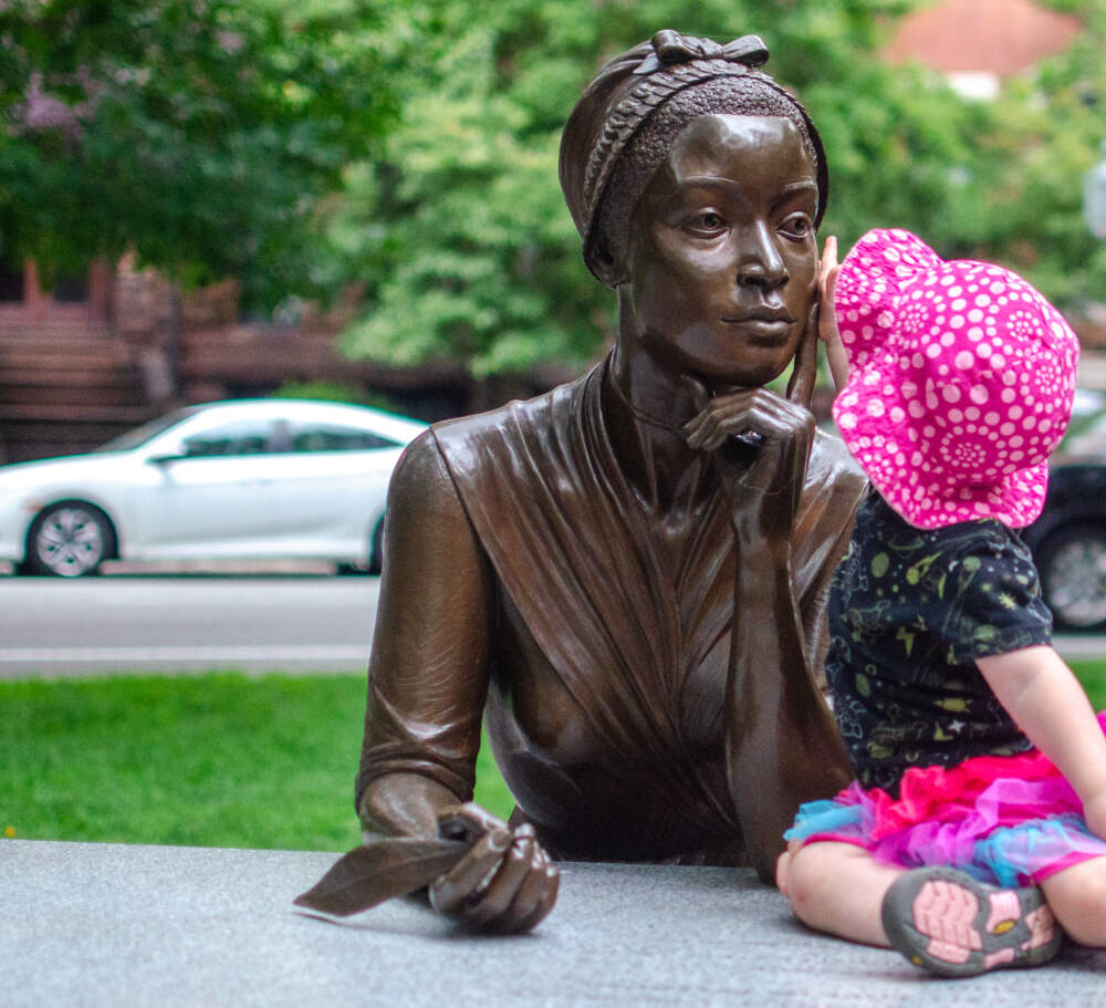 A toddler sits before a sculpture of poet Phillis Wheatley. (Sharon Brody/WBUR)