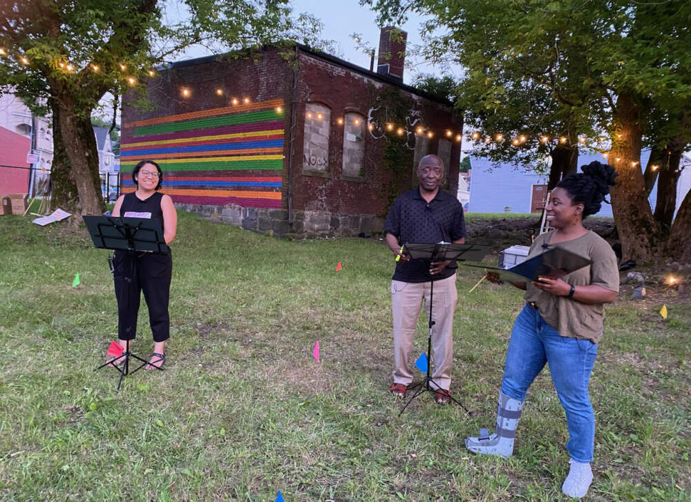 Ruby Reyes and Pastor Bisi Aseve reenact their fight for green space in a rehearsal of the play Dorchester Weather, led by playwright Jaronzie Harris (on the right). (Paula Moura/WBUR)