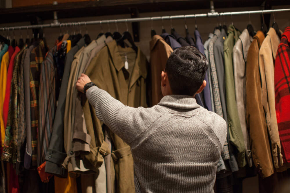 Young man looking through clothes rail in vintage shop. (Getty Images)