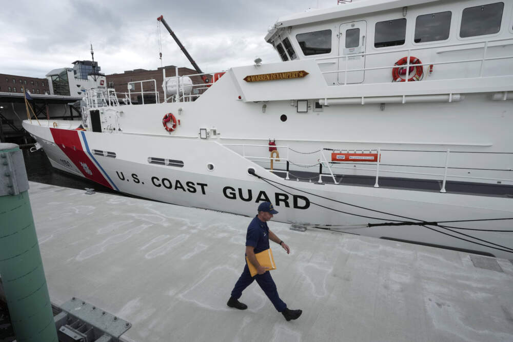 The U.S. Coast Guard Cutter Warren Deyampert is docked as a member of the Coast Guard walks past on June 20, 2023, at Coast Guard Base Boston. (Steven Senne/AP)