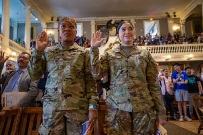Resla Augustin of Haiti and Beatriz Miwa of Brazil, both in the Army National Guard, stand and take the Oath of Allegiance during a naturalization ceremony at Faneuil Hall. (Jesse Costa/WBUR)