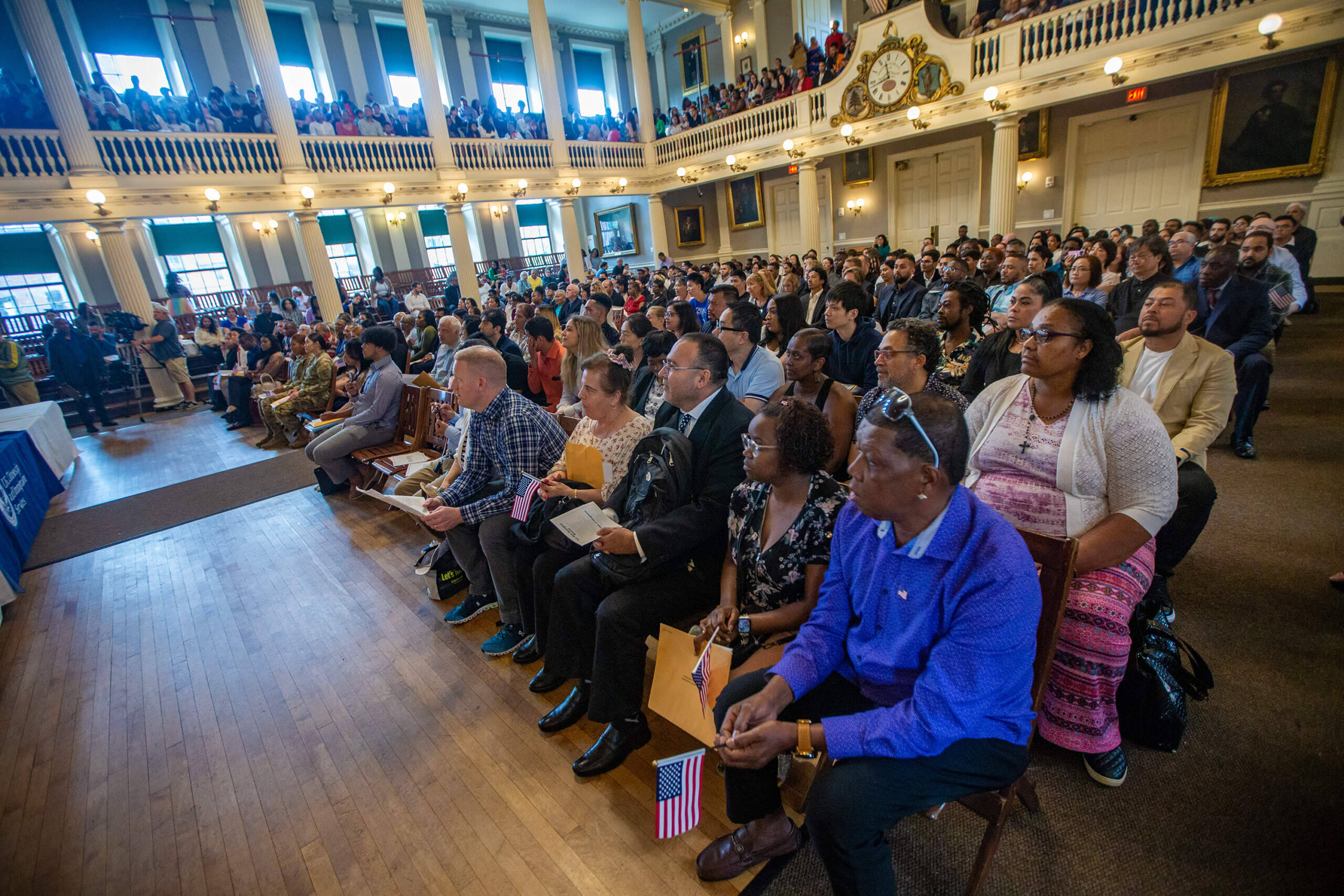 New citizens listen to federal Judge Janet Bostwick speak during a naturalization ceremony at Faneuil Hall. (Jesse Costa/WBUR)