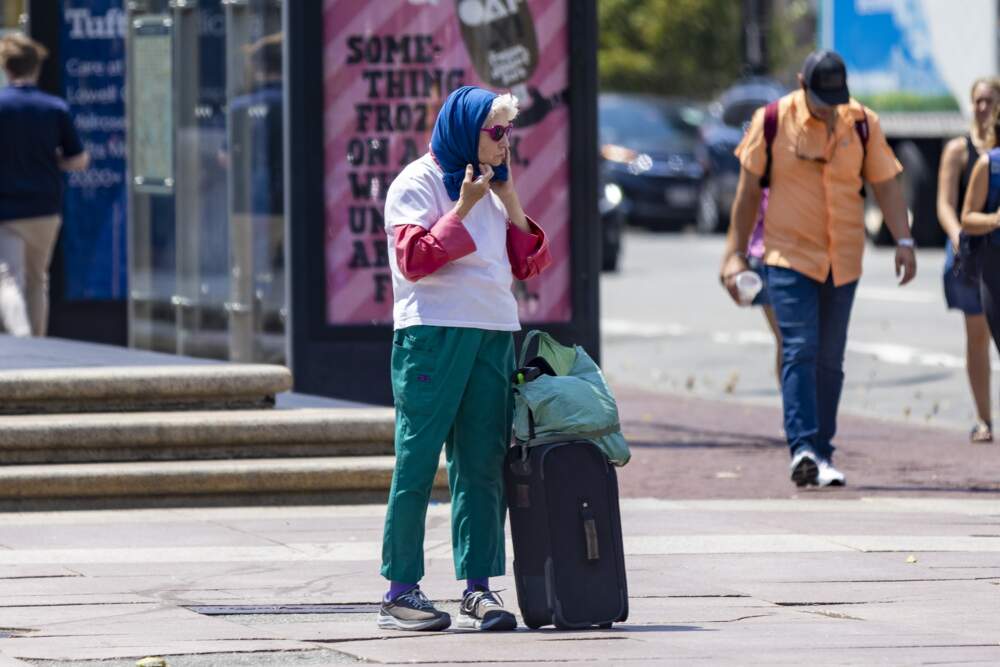 A woman puts a scarf on her head to protect herself from the sun in Copley Square. (Jesse Costa/WBUR)