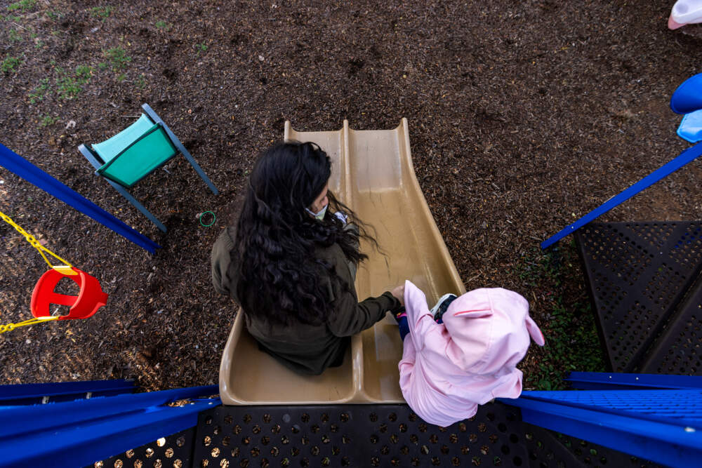 A mother and her two-year-old daughter in the play yard at the shelter where they are staying. (Jesse Costa/WBUR)