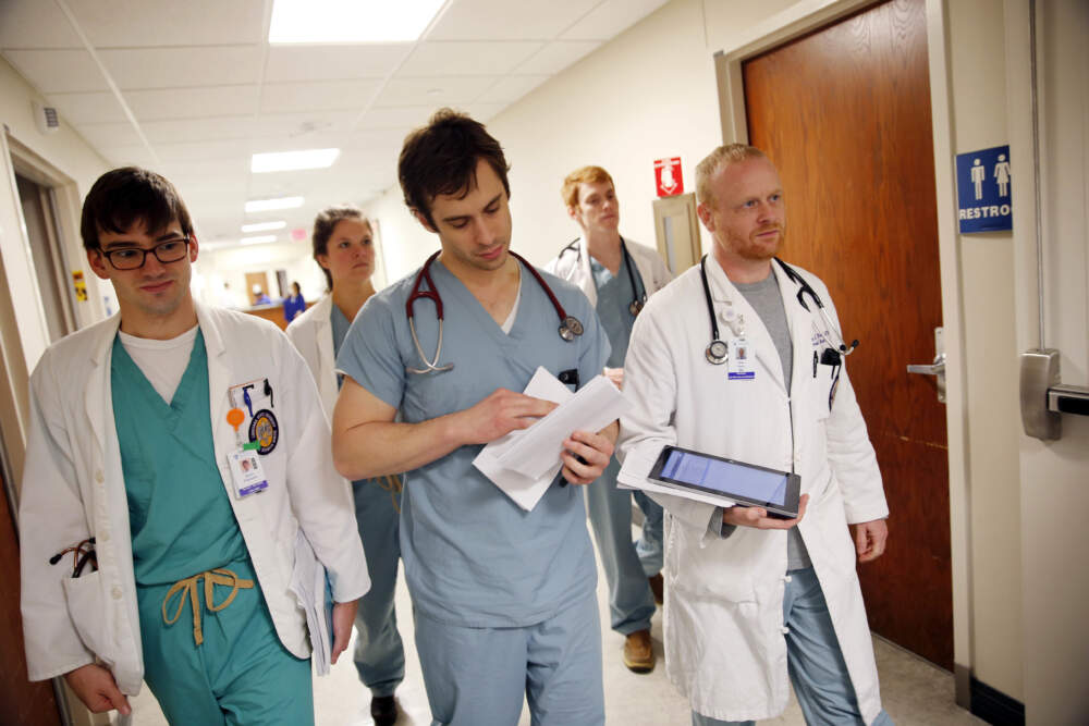 In a May 6, 2016 photo, medical residents Dr. Wes Penn, right, and Dr. Cameron Collier, center, walk with medical students down a hallway during their daily rounding at Our Lady of the Lake Regional Medical Center in Baton Rouge, Louisiana. (Gerald Herbert/AP)