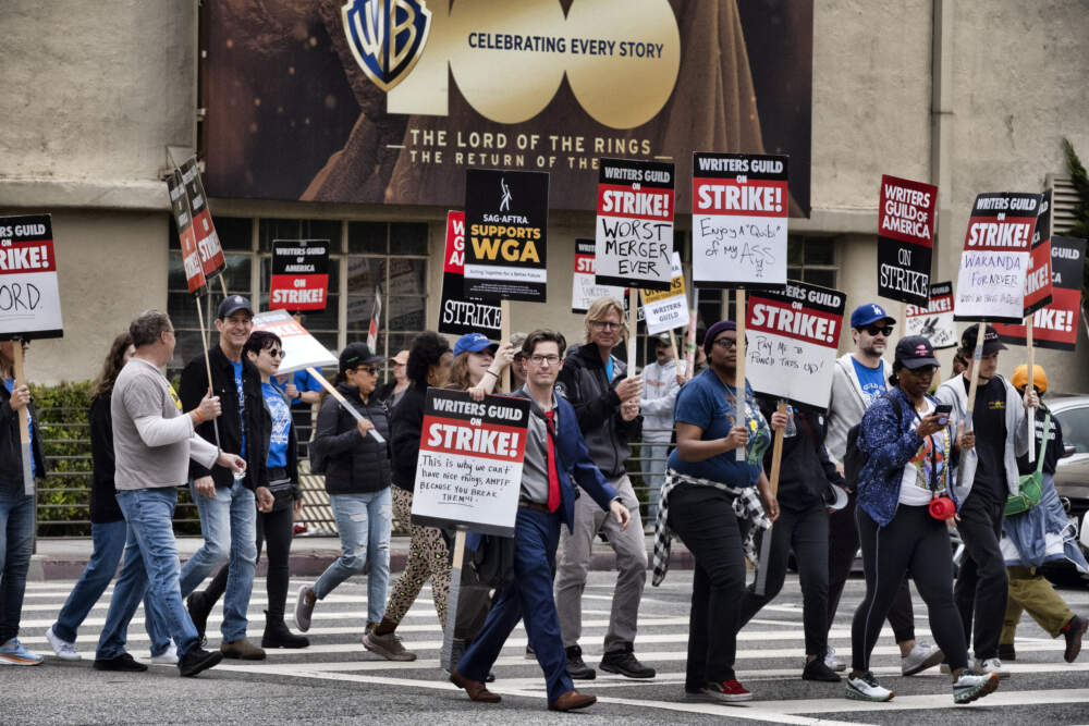 Picketers pass near a studio entrance during a Writers Guild rally outside Warner Bros. Studios. (Richard Vogel/AP)