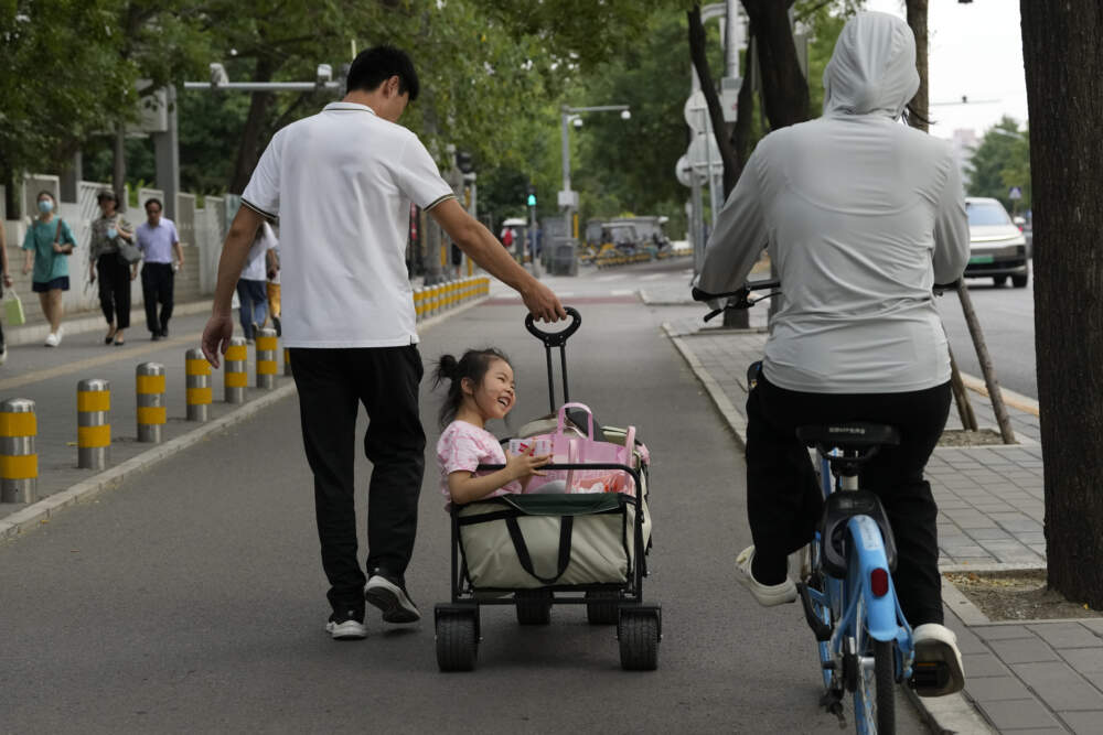 A child is pulled in a trolley in the afternoon in Beijing, Thursday, July 20, 2023. (Ng Han Guan/AP)