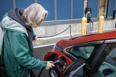Loie Hayes plugs in her car at a charging station in Boston. (Robin Lubbock/WBUR)