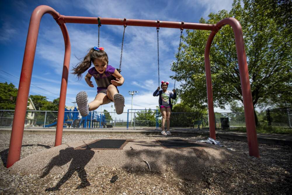 Sisters play on the swings at McLaughlin Park in Mission Hill. (Jesse Costa/WBUR)