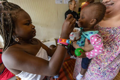 A 9-year-old feeds ice cream to her 1-year-old sister during an ice cream social in late July at the Catholic Charities new emergency shelter for the homeless in Brighton. (Jesse Costa/WBUR)