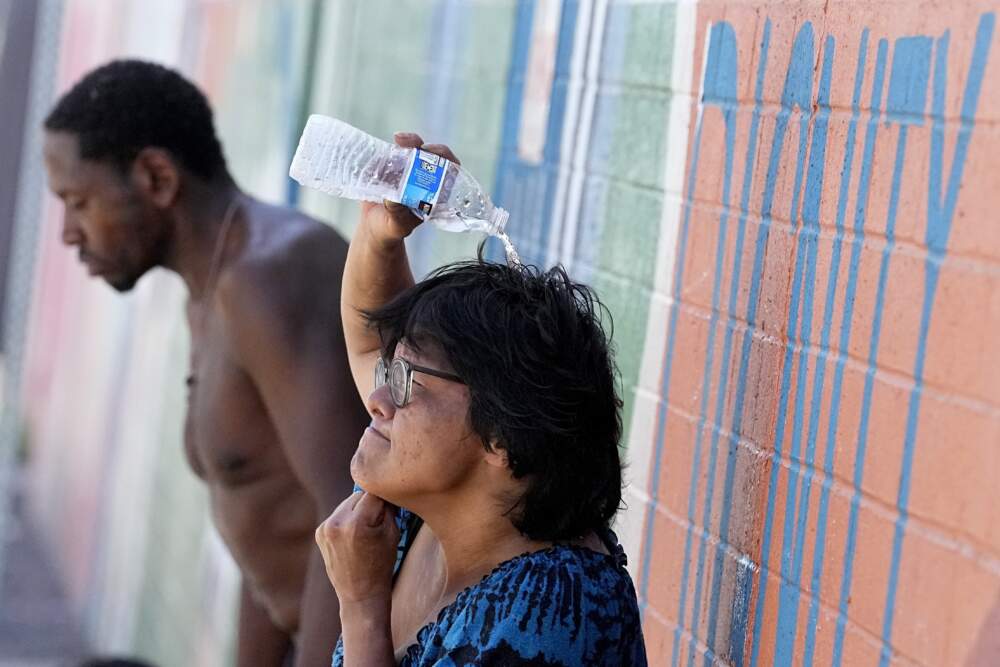 People, who are homeless, try to cool down with chilled water outside the Justa Center, a day center for homeless people 55 years and older. (Matt York/AP)