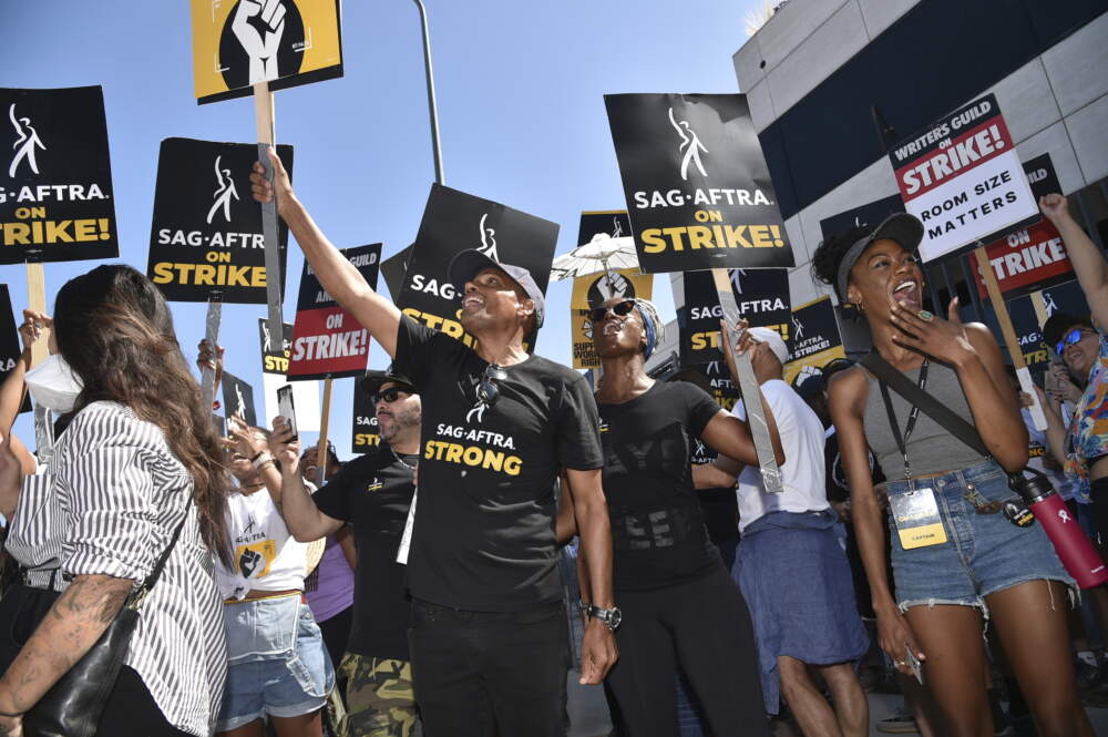 Picketers carry signs on the picket line outside Universal Studios. (Richard Shotwell/Invision/AP)