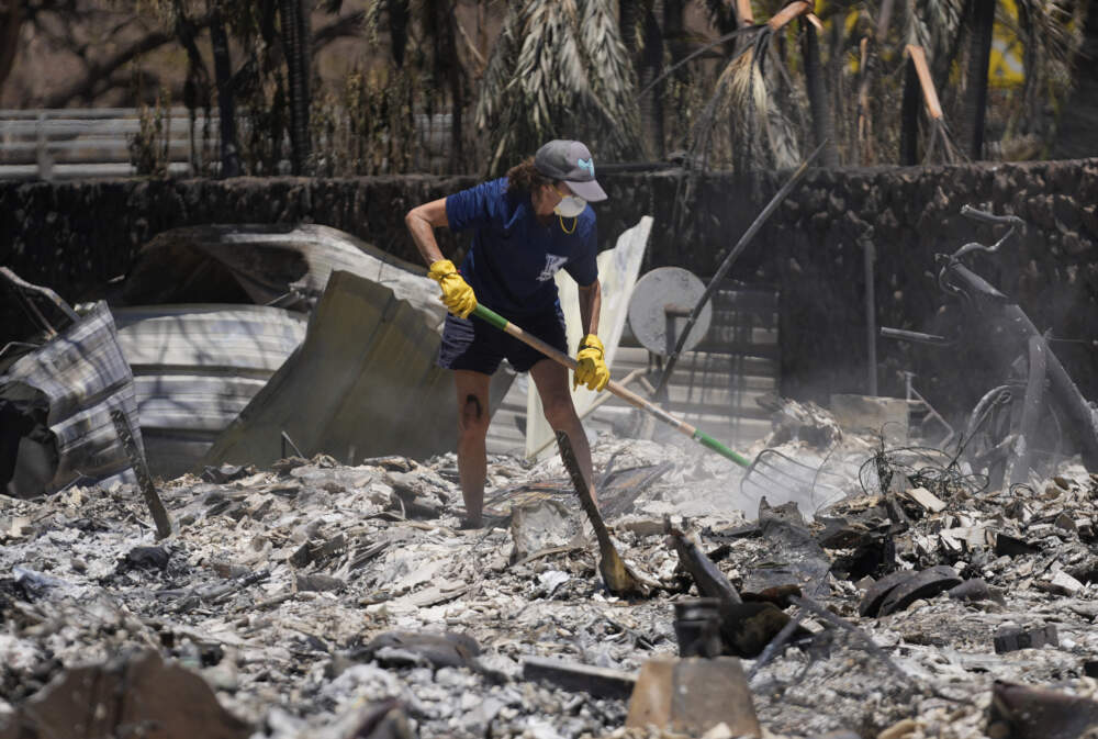 A woman digs through rubble of a home destroyed by a wildfire. (Rick Bowmer/AP)