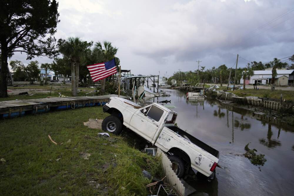 A pickup truck with an American flag tied to sits halfway into a canal in Horseshoe Beach after the passage of Hurricane Idalia. (Rebecca Blackwell/AP)