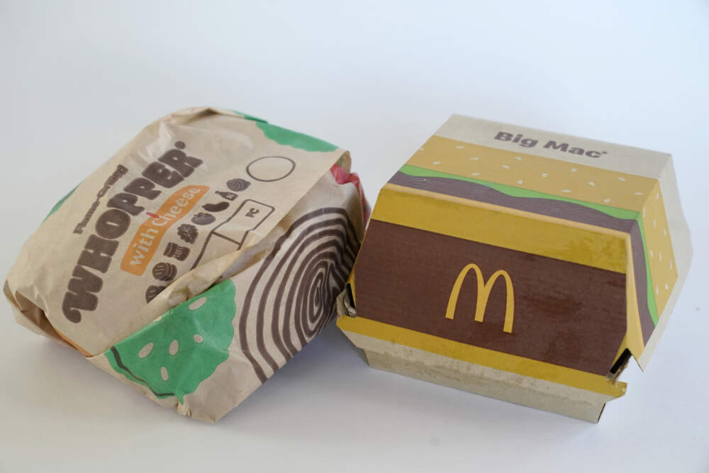 A Burger King Whopper in a wrapper, left, rests next to a McDonald's Big Mac in a container, in Walpole, Mass. Environmental and health groups are pushing dozens of fast food companies, supermarket chains and other retail outlets to remove PFAS from their packaging. (Steven Senne/AP)