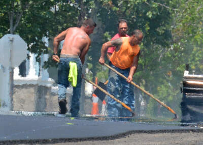 Heat waves distort the view of a work crew as they resurface a road in South Boston. (Chris Christo/MediaNews Group/Boston Herald via Getty Images)