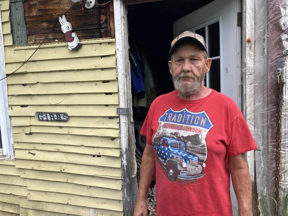 Andrew Gibbs, of Wolcott, stands in front of his home which was ravaged by flood waters a month ago. Hundreds of Vermonters like Gibbs face a difficult choice: should they rebuild? (Liam Elder-Connors?Vermont Public)