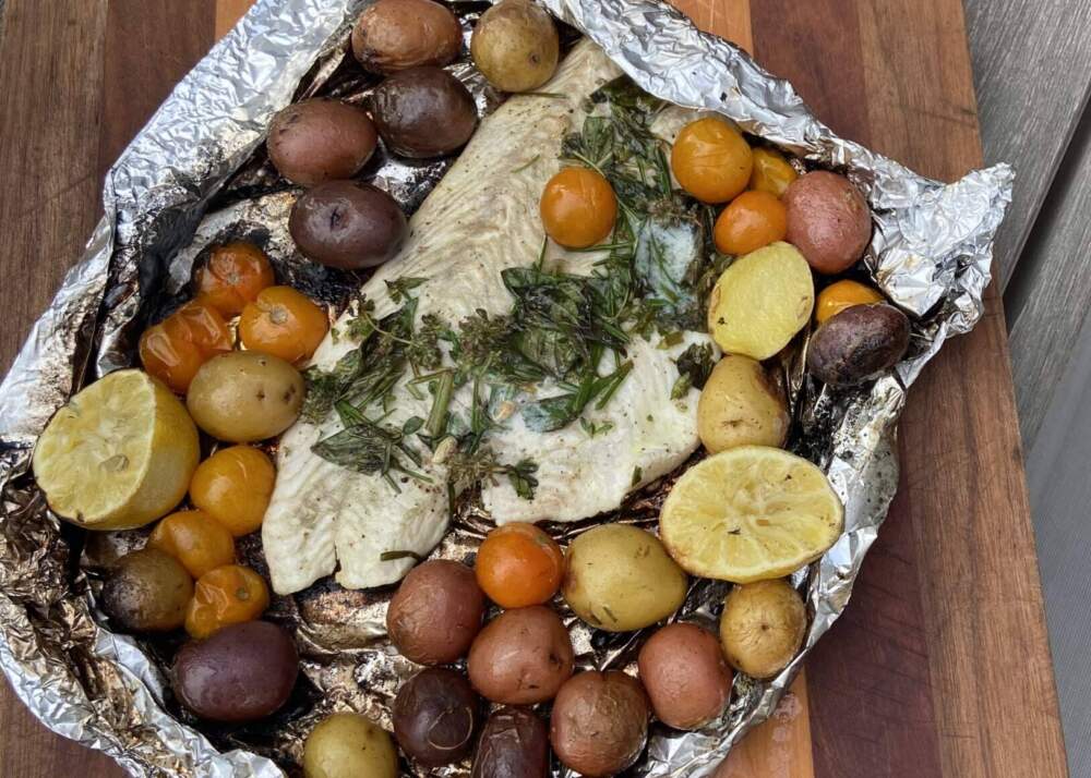 Foil-wrapped fire-grilled fish with baby potatoes, cherry tomatoes and herbs. (Kathy Gunst/Here & Now)