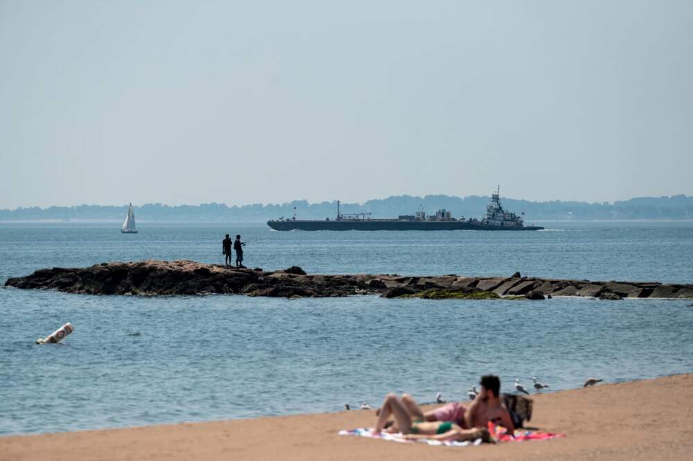 New Haven residents take refuge from the August heat by the waterside at Lighthouse Point Park as boats leave the nearby harbor in 2022. (Ryan Caron King/Connecticut Public Radio)