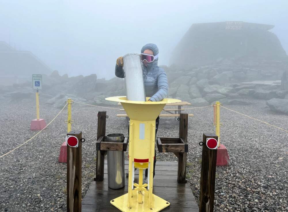 The Mount Washington summit has recorded its wettest July. In this photo, weather observer Alexis George measured precipitation on July 29, 2023 — at that point, giving the summit a total of 16.91 inches of precipitation measured for July 2023. This surpasses the previous record of 16.85 inches set in July of 1996 and is 7.98 inches higher than average. (Mount Washington Observatory via NHPR)