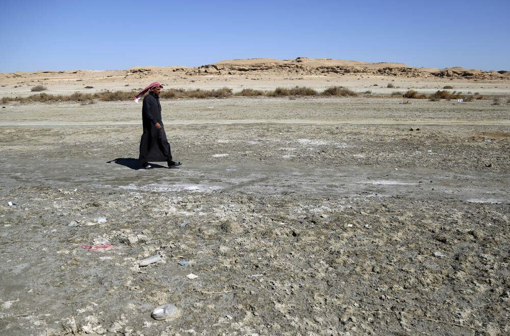 A man walks on saline soil near Razzaza Lake, also known as Lake Milh, Arabic for salt, in the Karbala governorate of Iraq, Feb. 14, 2022. The lake was once a tourist attraction known for its beautiful scenery and an abundance of fish that locals depended on. Dead fish now litter its shores and the once-fertile lands around it have turned into a barren desert. (Hadi Mizban/AP)