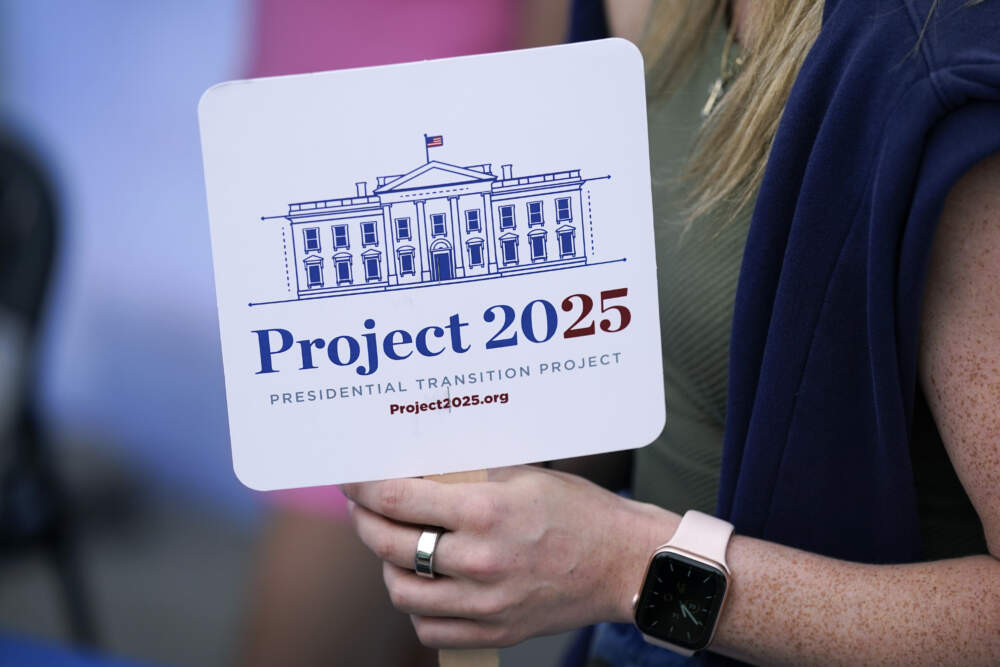 A woman holds a Project 2025 fan in the group's tent at the Iowa State Fair, Aug. 14, 2023, in Des Moines, Iowa. (Charlie Neibergall/AP)