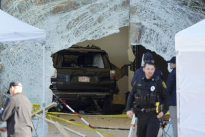 An SUV rests inside an Apple store behind a large hole in the glass front of the store, Nov. 21, 2022, in Hingham, Mass. (Steven Senne/AP)