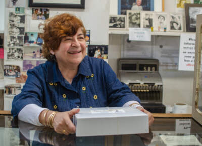 Roula Kappas, the owner of New Paris Bakery, hands a box of pastries to a customer days before the shop in Brookline closes after more than 100 years in business. (Sharon Brody/WBUR)