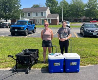 Sherisse Salter (left) and Angalena Negron distribute meals at Elmwood Gardens in Manchester with New Hampshire Hunger Solutions. They worked to expand participation in summer meals sites in the city. (Kate Dario/NHPR)