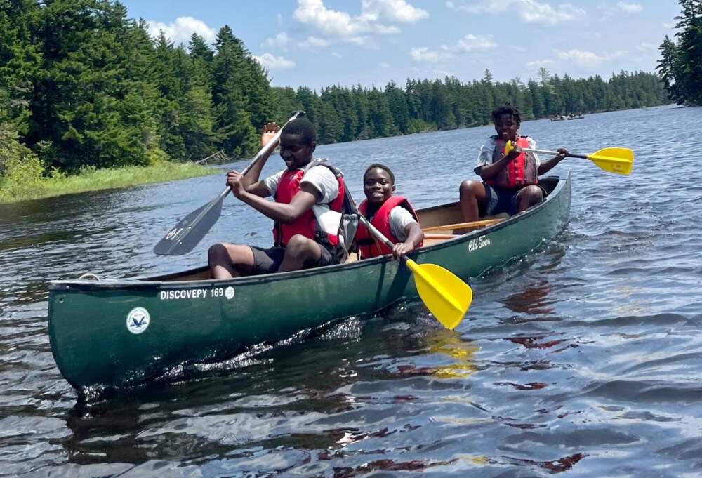 Three boys paddling on the Cupsuptic River during a #WeOutside trip this summer. The program brought groups of asylum seeker students on weekly outdoor trips. (Esta Pratt-Kielley/Maine Public)