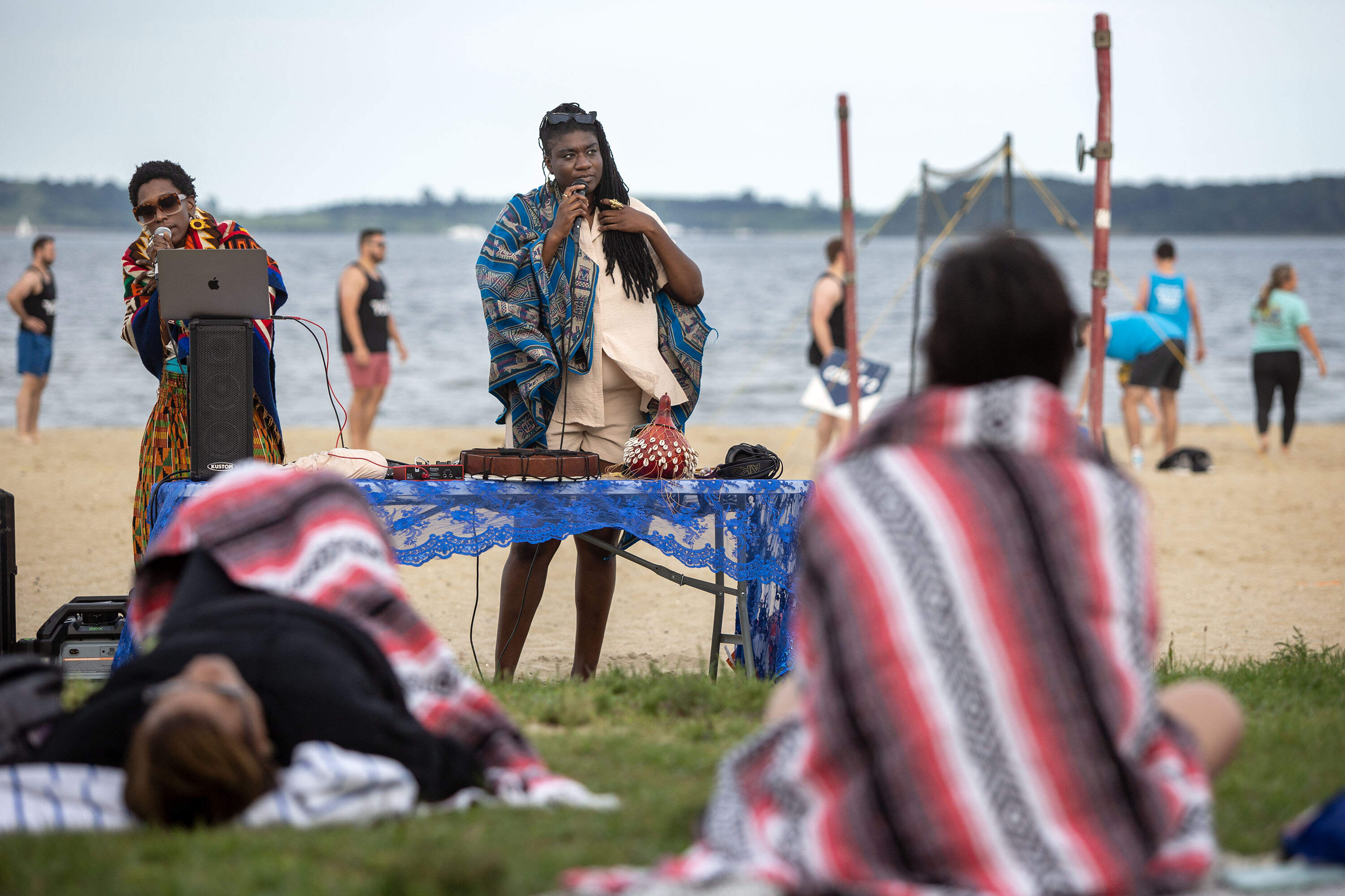 Performance artist Dzidzor glances across the beach as vocalist Thamanai sings at a rest activation at Carson Beach in Boston. (Robin Lubbock/WBUR)