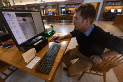 Researcher Max Chapnick combs through editions of the Saturday Evening Gazette on microfilm to locate stories written by Louisa May Alcott in the 1850s at the Boston Public Library. (Jesse Costa/WBUR)