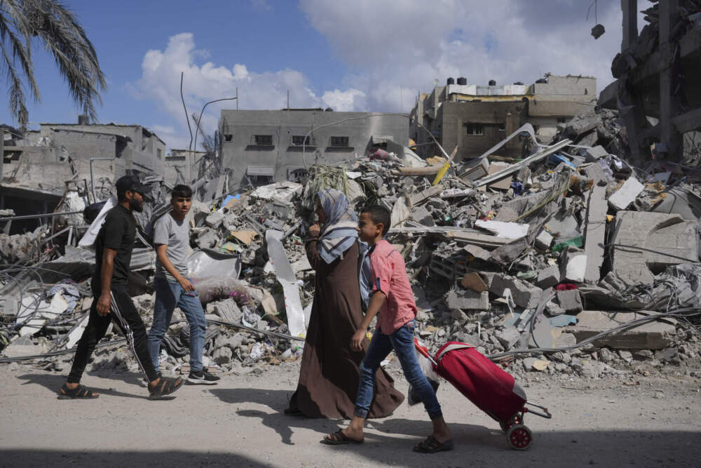 Palestinians walk next to the buildings destroyed in Israeli airstrikes in Bureij refugee camp, Gaza Strip. (Hatem Moussa/AP)