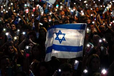 People hold Israeli national flags and display their lit mobile phones during a rally in support of the people of Israel, in Buenos Aires on October 9, 2023, following the October 7 shocking deadly attack on Israel by Palestinian militant group Hamas. (LUIS ROBAYO/AFP via Getty Images)