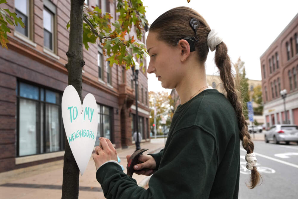 Miia Zellner, an art teacher from Turner, Maine, attaches a heart cut-out with a message of positivity to a tree in downtown Lewiston, Maine on Thursday, Oct. 26. (Robert F. Bukaty/AP)