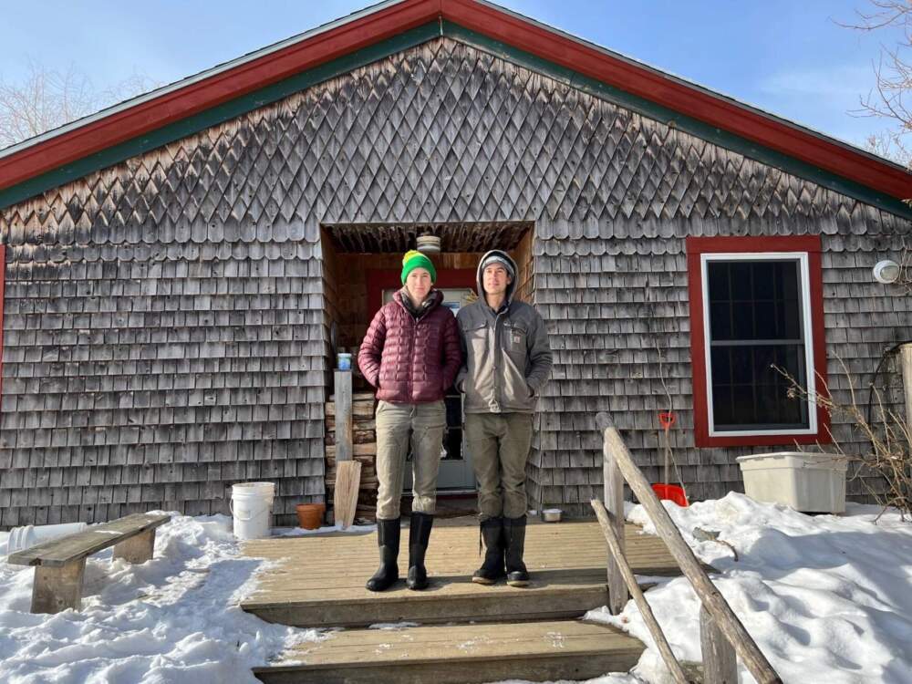 Johanna Davis and Adam Nordell stand outside of their house at Songbird Farm, an organic vegetable and grain farm they operated in Unity that was closed due to PFAS contamination. (Kevin Miller/Maine Public)