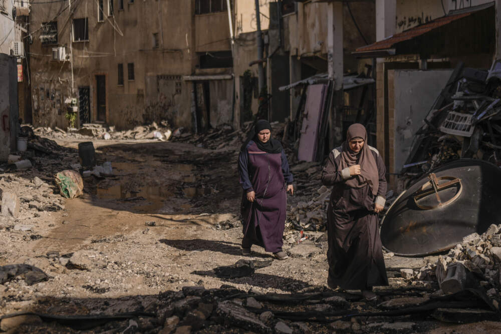 Palestinian women walk past an area damaged after an Israeli military raid in Jenin refugee camp in the West Bank. (Majdi Mohammed/AP)