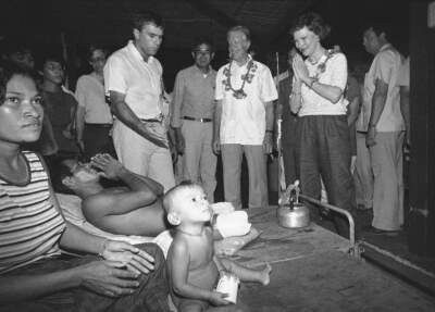 Rosalynn Carter returns the traditional greeting she receives from a double amputee as she and her husband, former President Jimmy Carter, second from right, visit a hospital at Khao-I-Dang, June 5, 1985.  The wounded Khmer has his wife and child with him in the hospital. Carter called for the U.S to resume diplomatic relations with Vietnam and help solve the Cambodian refugee problem. (Gary Mangkorn/AP)