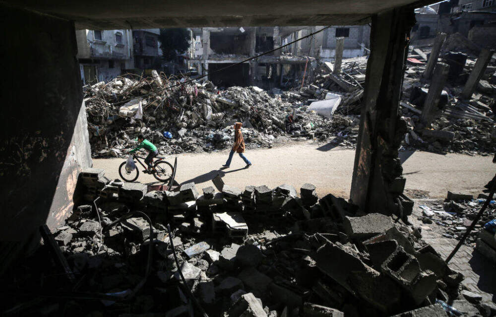 Palestinians are walking amid the rubble of destroyed buildings in Bureij camp in the central Gaza Strip on November 30, 2023, during a truce in the fighting between Israel and the Palestinian group Hamas. (Majdi Fathi/NurPhoto via Getty Images)