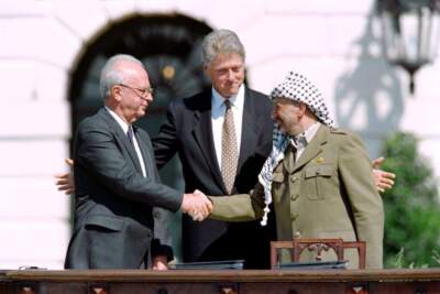 US President Bill Clinton (C) stands between PLO leader Yasser Arafat (R) and Israeli Prime Minister Yitzahk Rabin (L) as they shake hands for the first time, on September 13, 1993 at the White House in Washington DC, after signing the historic Israel-PLO Oslo Accords on Palestinian autonomy in the occupied territories. AFP PHOTO J.DAVID AKE (Photo by J. DAVID AKE / AFP) (Photo by J. DAVID AKE/AFP via Getty Images)